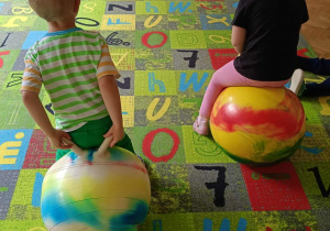 Dzieci skaczą na piłkach skoczkach.