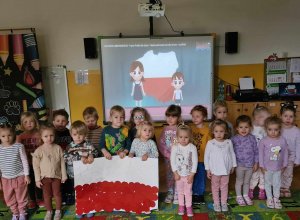 dzieci stojące na baczność trzymają flagę