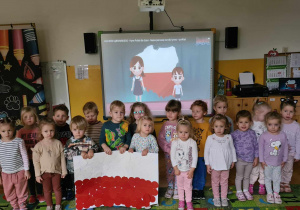 dzieci stojące na baczność trzymające flagę Polski